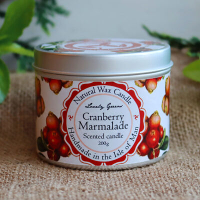 Front view of a cranberry candle tin. The tin is round and decorated with a label featuring illustrations of red cranberries on a white background.